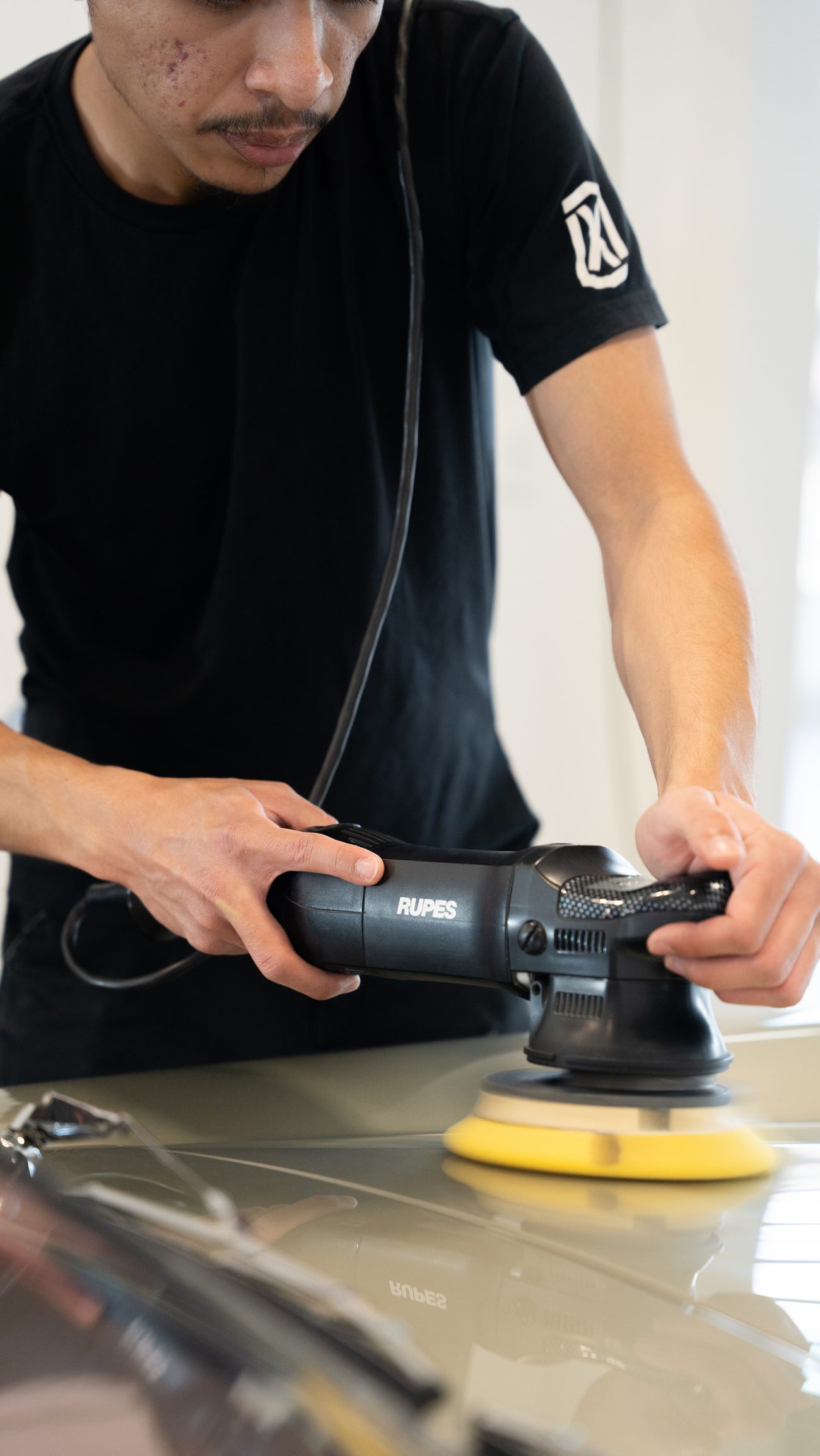 A tech running a polisher on a champagne panel