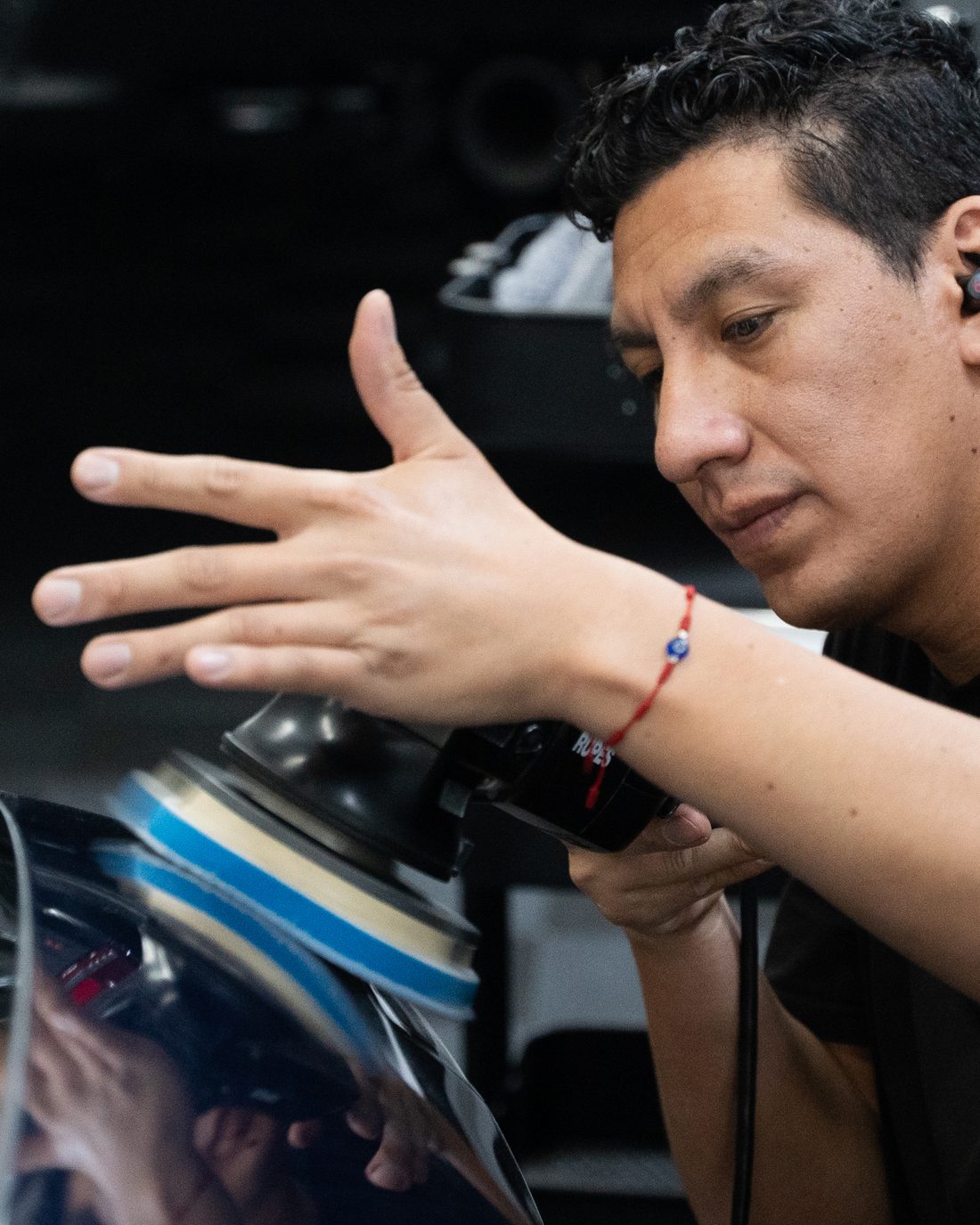 A tech checking a black panel by hand before the next polishing pass