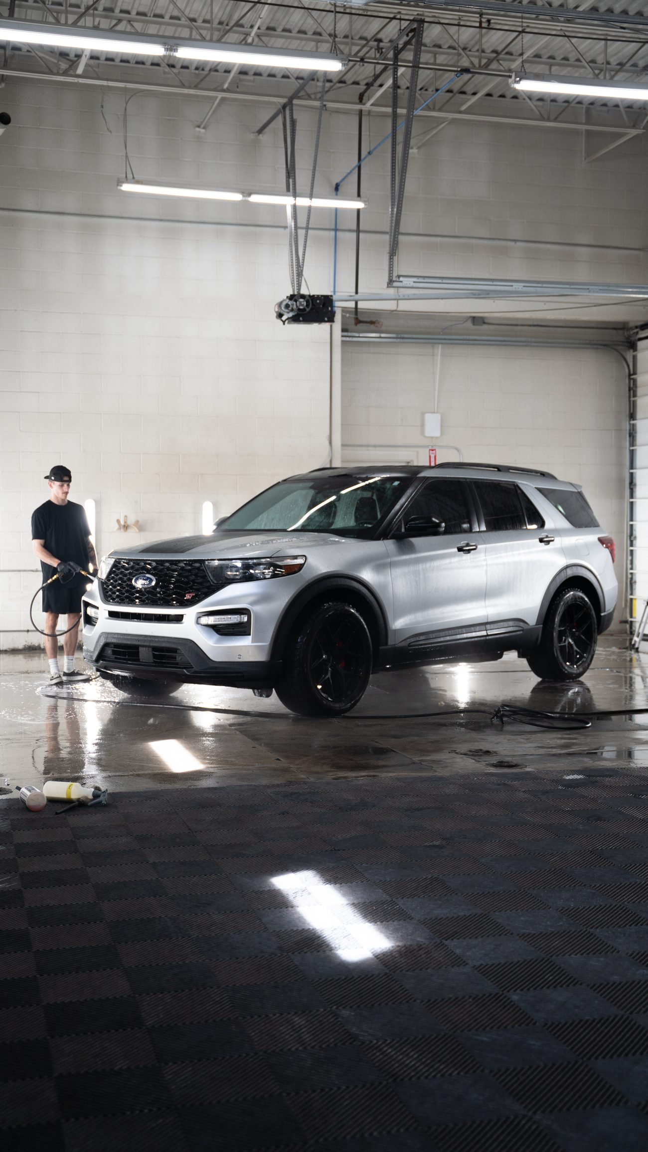 Two LUXE techs washing a silver SUV in the wash bay
